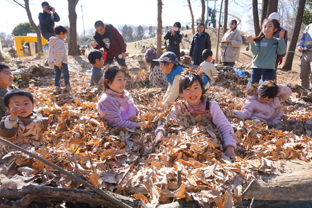 落ち葉を集めて、鳥の巣のようなふかふかな堆肥場で笑顔の子どもたち。