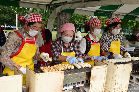 四人の女性が、集中して焼き団子を焼いている様子。