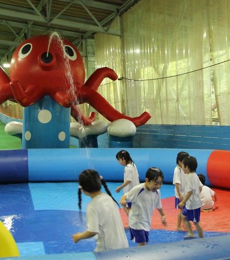 蛸型の巨大散水エアー遊具から水が出てきて、濡れながらはしゃぐ園児たち