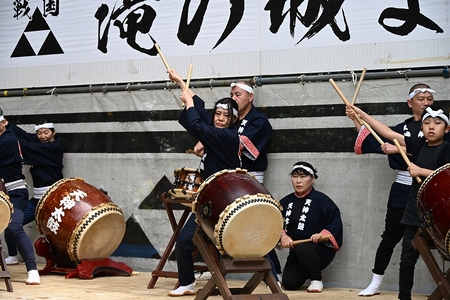 バチを両手に掲げて太鼓を叩く人々
