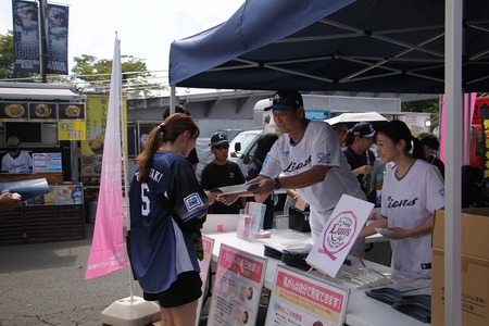 鳥越コーチとYUUMIさんが啓発資料を手渡している様子